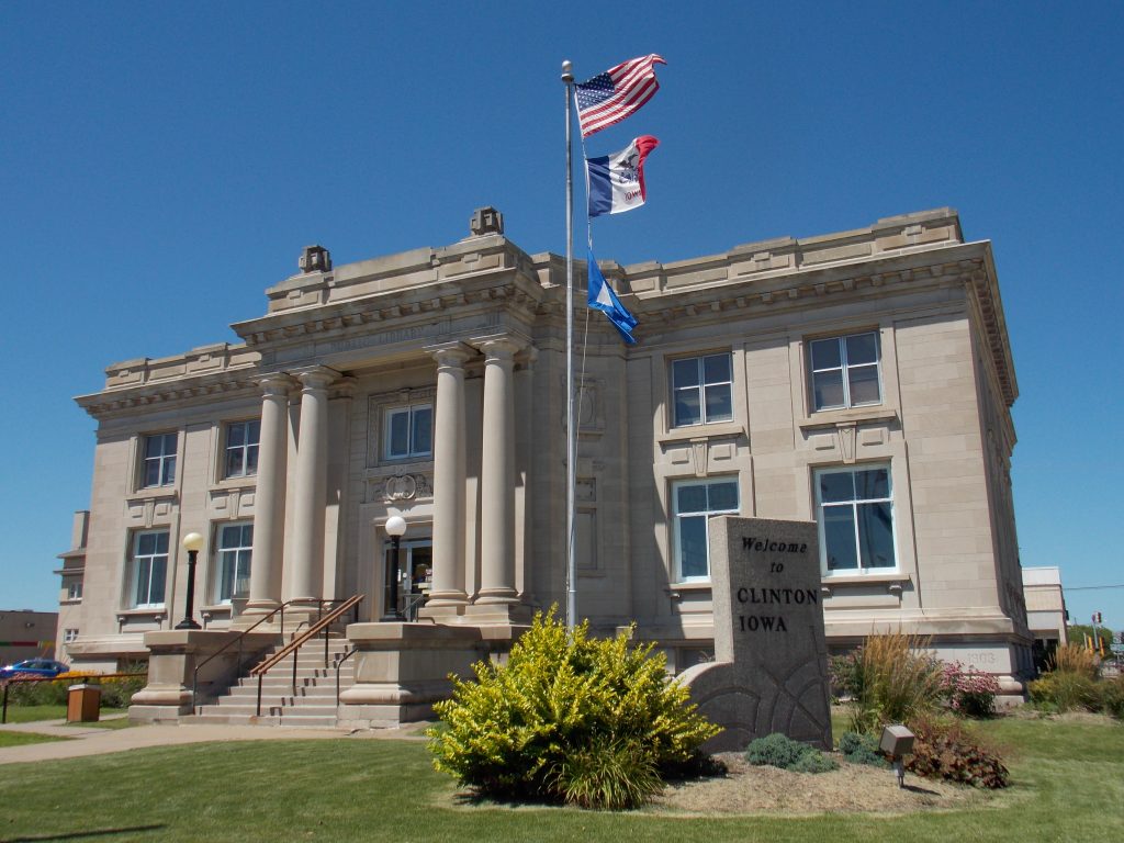 The historic, Beaux-Arts style Clinton Public Library building, featuring a limestone exterior and prominent columns at the entrance.